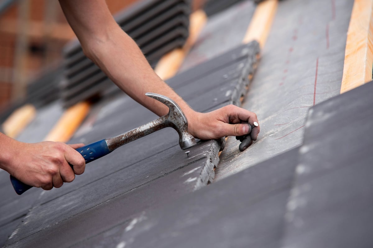Skilled builder placing roofing tiles
